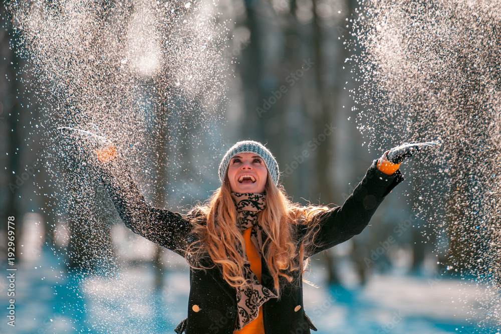 阳光明媚的冬日，微笑的女人向空中扔雪