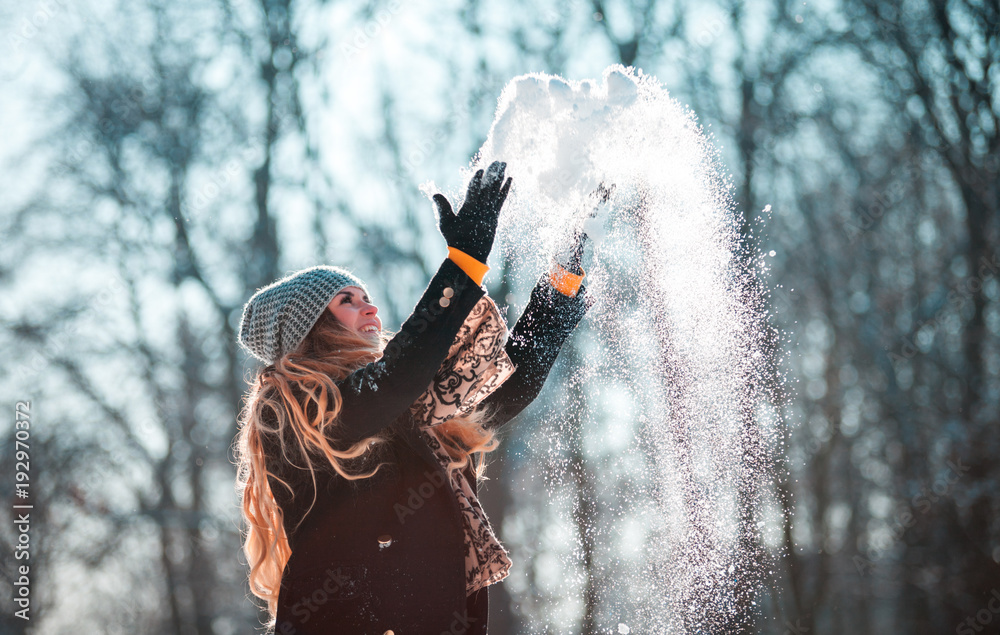 阳光明媚的冬日，微笑的女人向空中扔雪