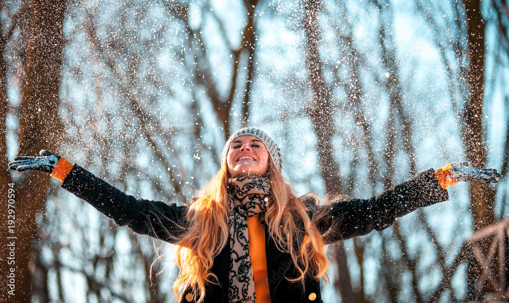 阳光明媚的冬日，微笑的女人向空中扔雪