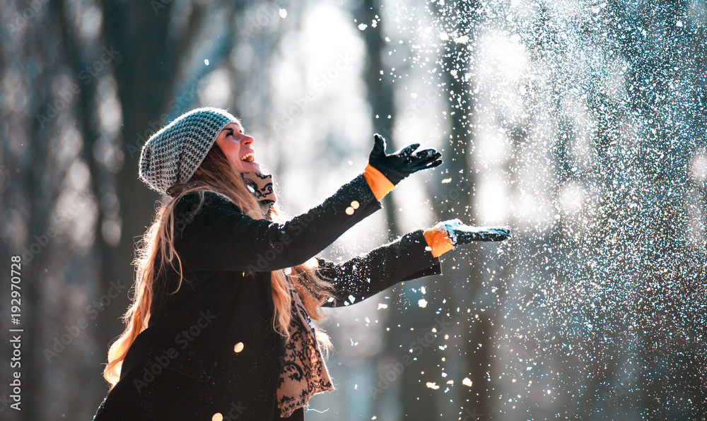 阳光明媚的冬日，微笑的女人向空中扔雪