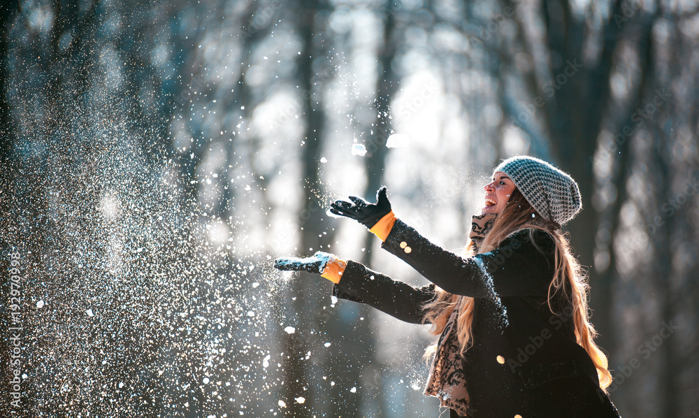 微笑的女人在阳光明媚的冬日向空中扔雪