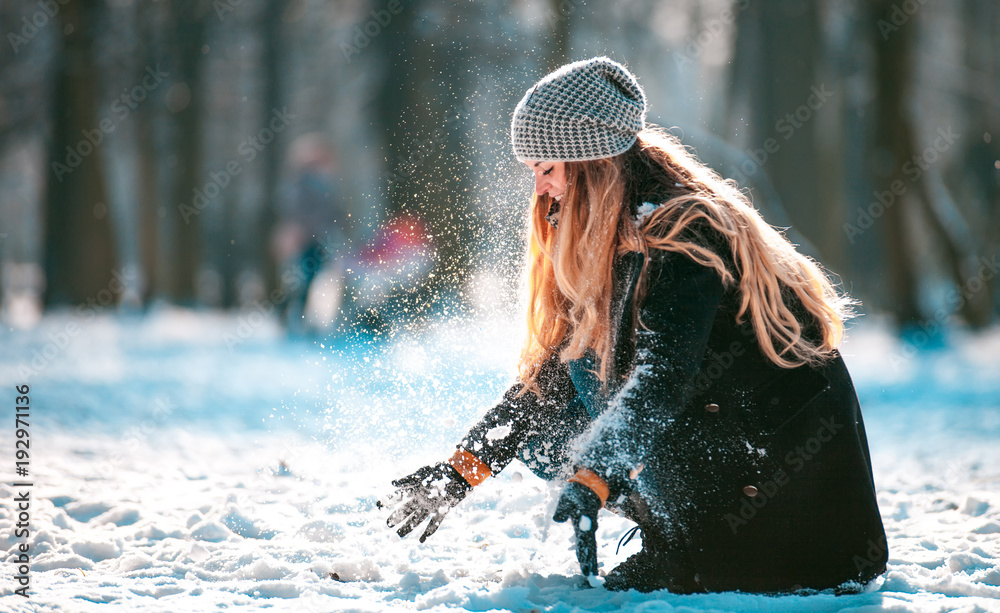 阳光明媚的冬日，微笑的女人向空中扔雪