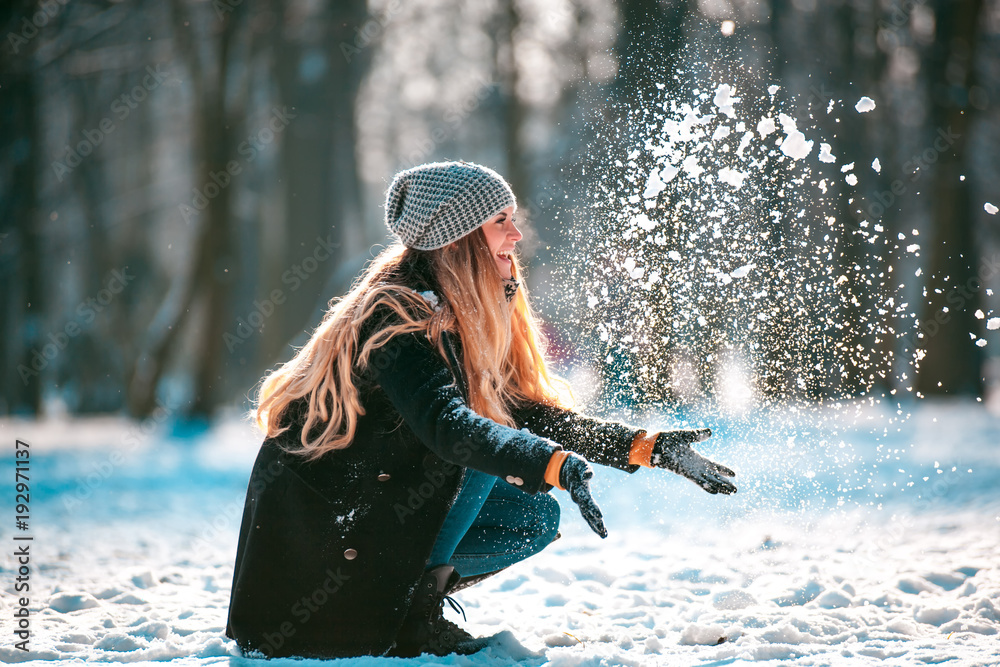 阳光明媚的冬日，微笑的女人向空中扔雪