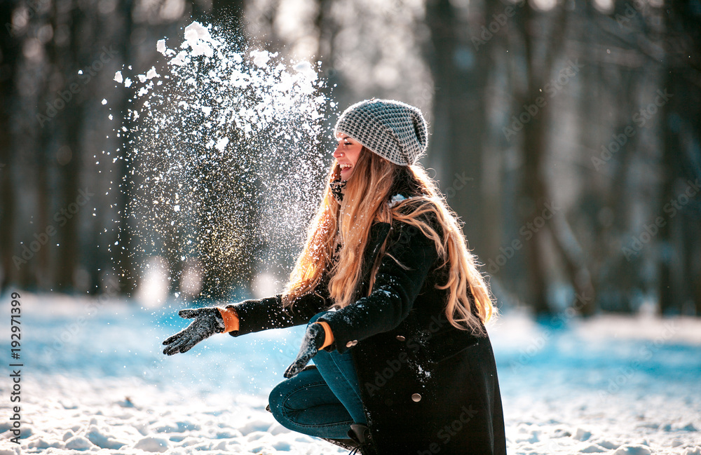 阳光明媚的冬日，微笑的女人向空中扔雪