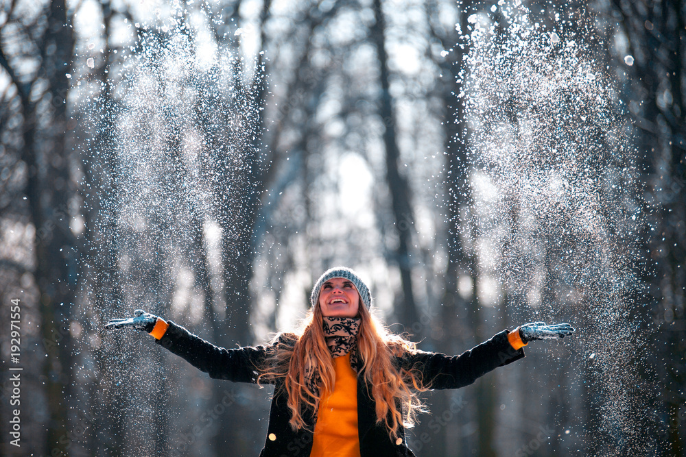 微笑的女人在阳光明媚的冬日向空中扔雪