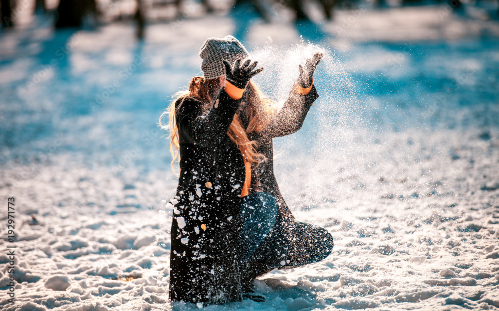 阳光明媚的冬日，微笑的女人向空中扔雪