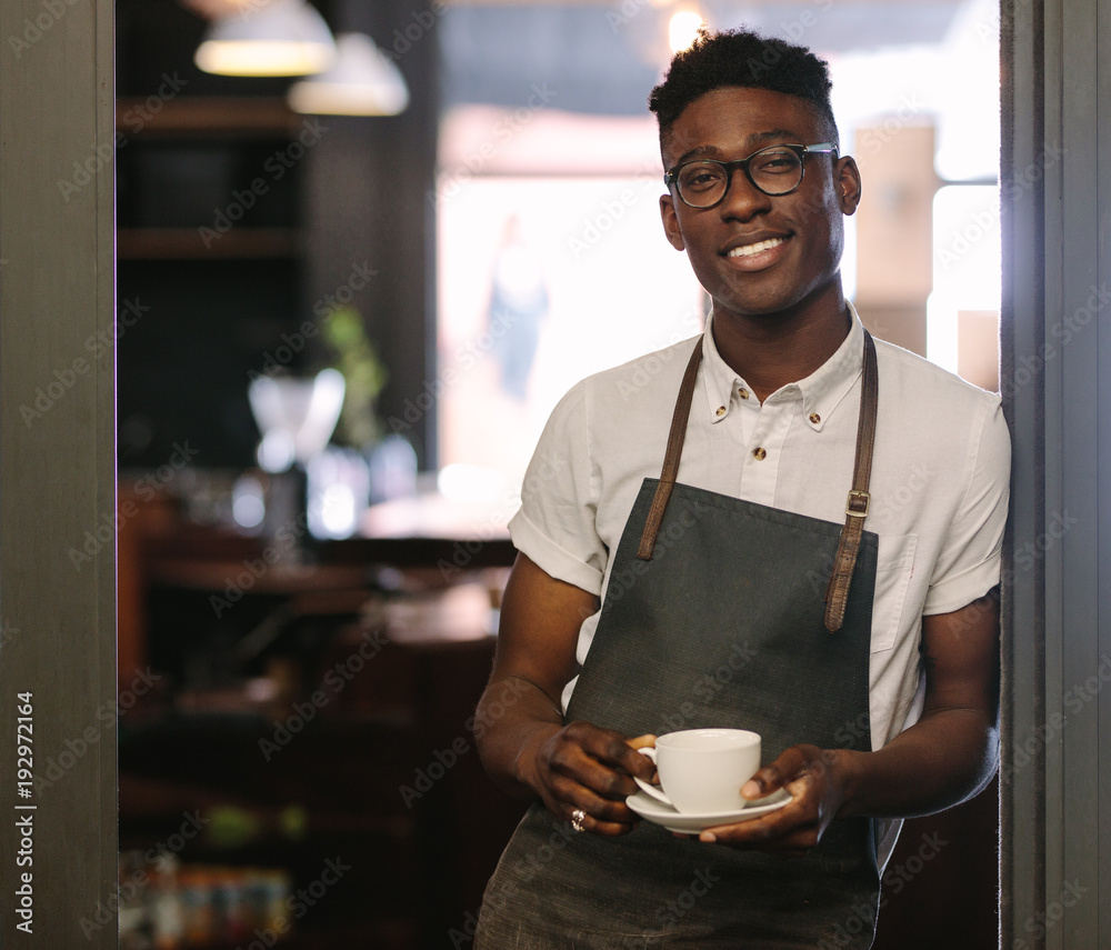 Café owner at his coffee shop holding a coffee cup