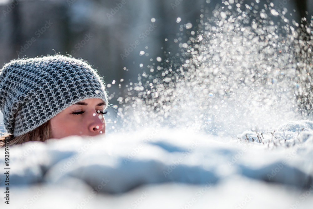 Winter woman blowing snow outdoor, flying snowflakes