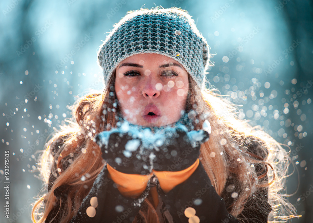 冬日女人在阳光明媚的日子里在户外吹雪，雪花纷飞