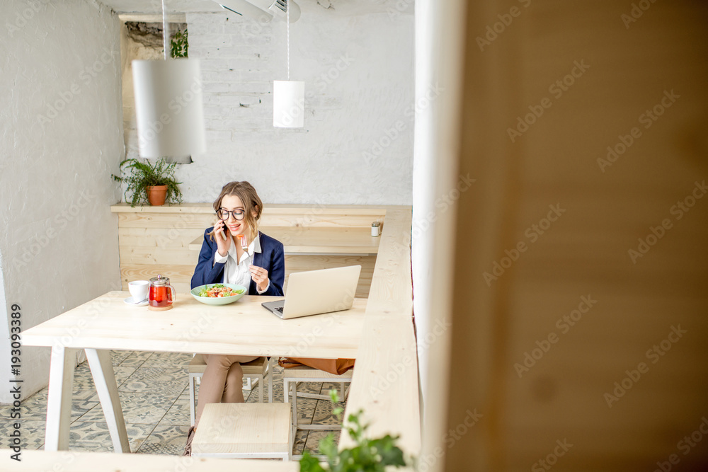 女商人午餐时坐在白色咖啡馆内部。视野开阔，有复制空间