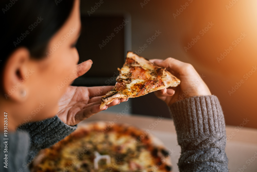 Woman holding slice of pizza. Close-up