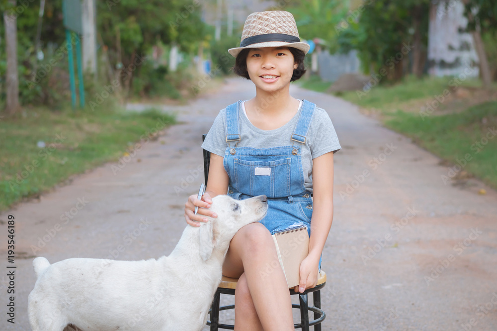 portrait of asian woman smiling hanppy outside with book and dog