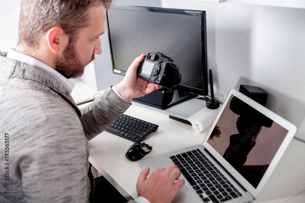 Photographer in home office working with laptop and looking at camera