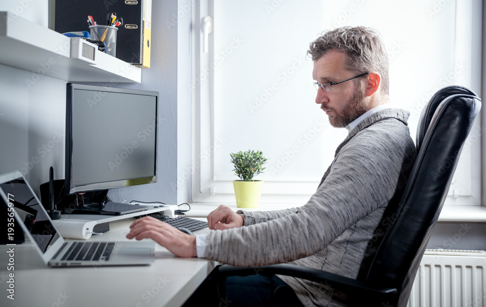 Middle age man working in home office with computer