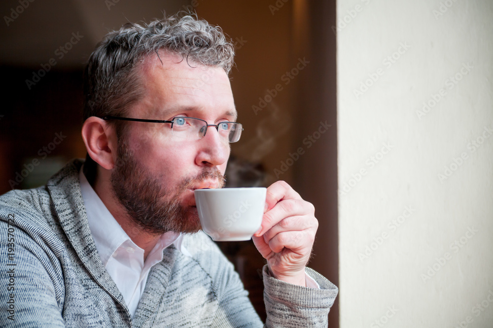 Confident man drinking cup of coffee in cafe