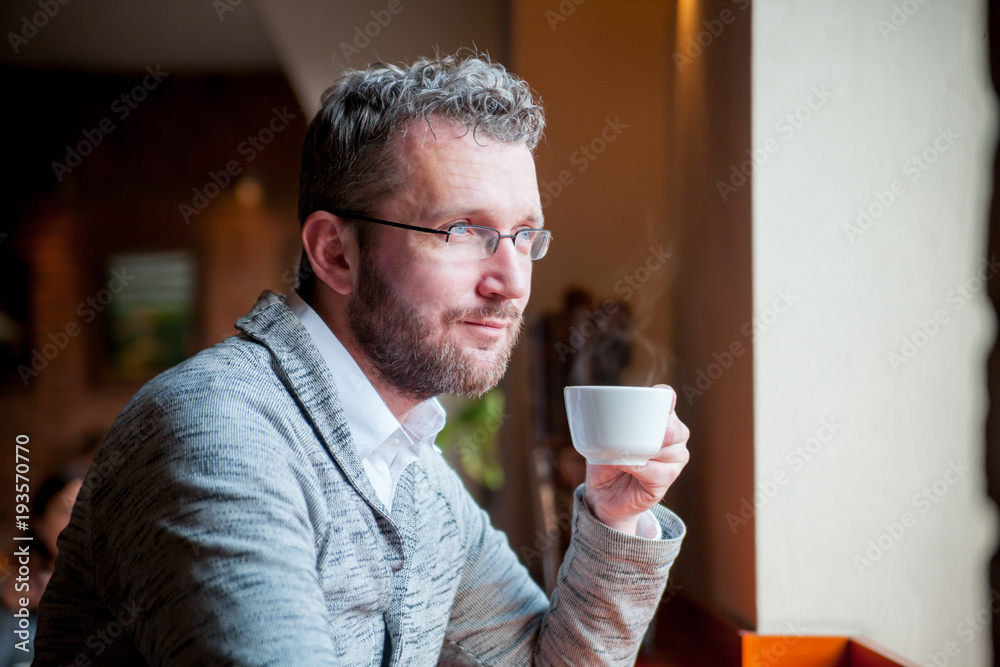 自信的男人在咖啡馆喝咖啡