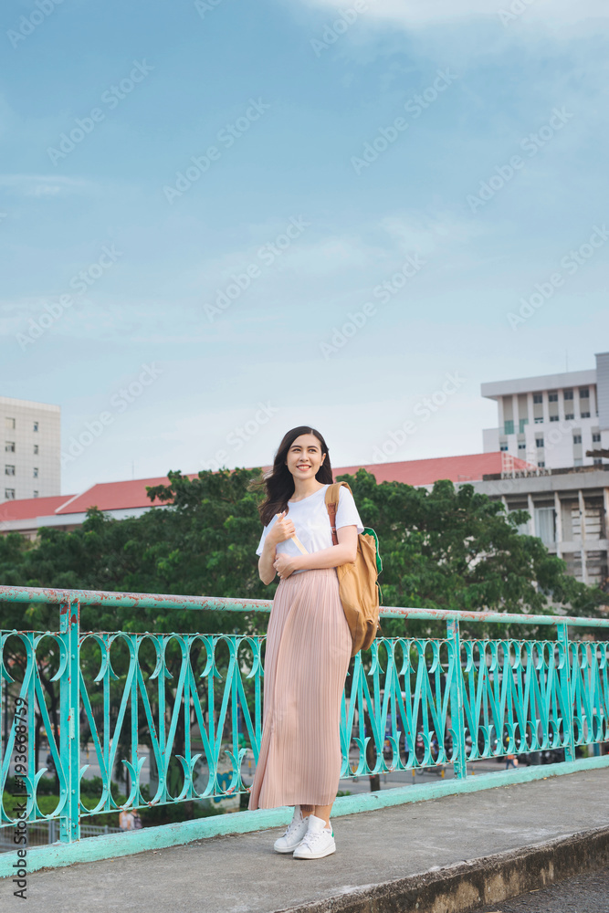 亚洲女孩手拿书走在城市景观的桥上的全长