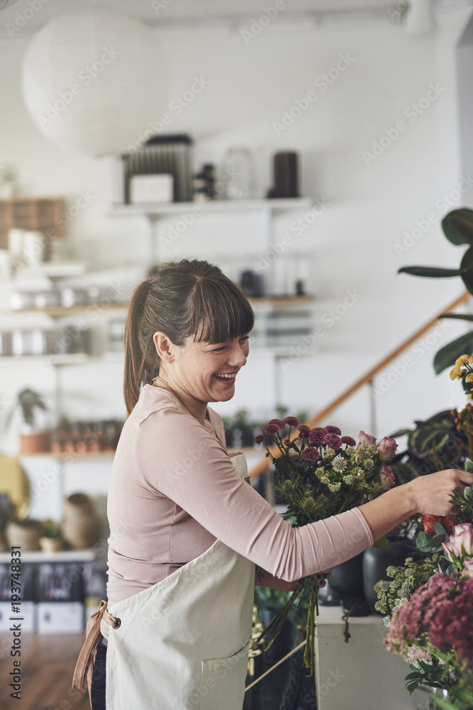 大笑的花店老板在她的店里布置花卉展览