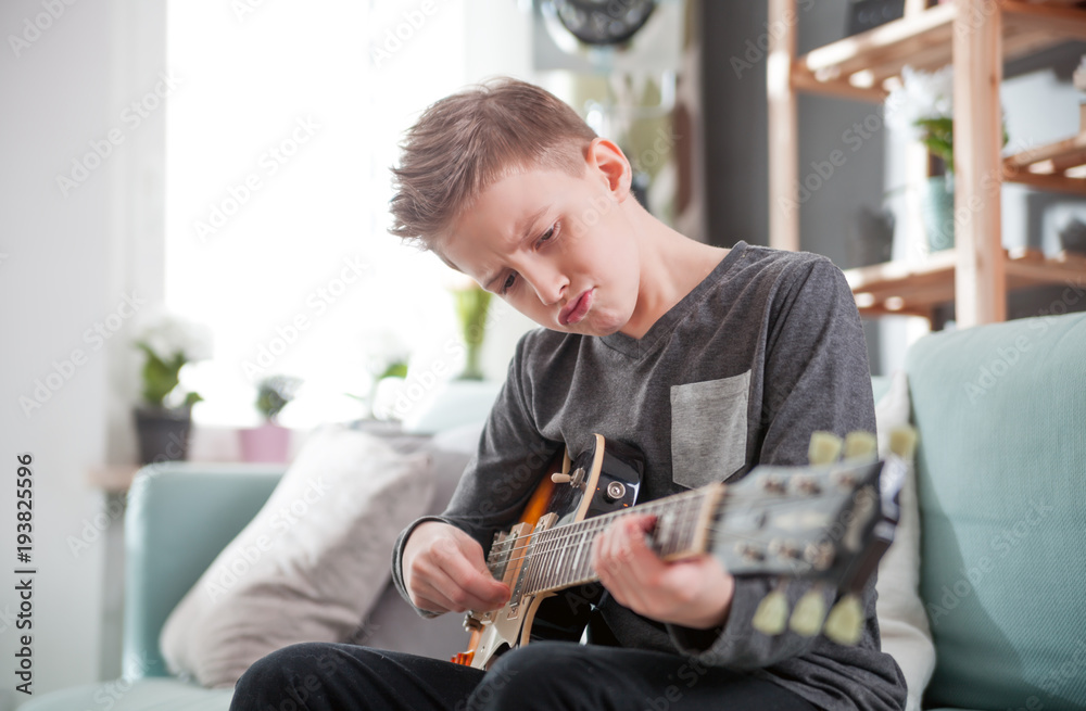 Young boy playing electric guitar at home