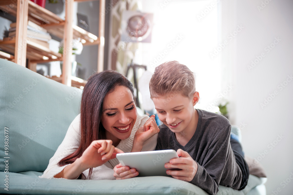 Mom and son using tablet together on sofa at home