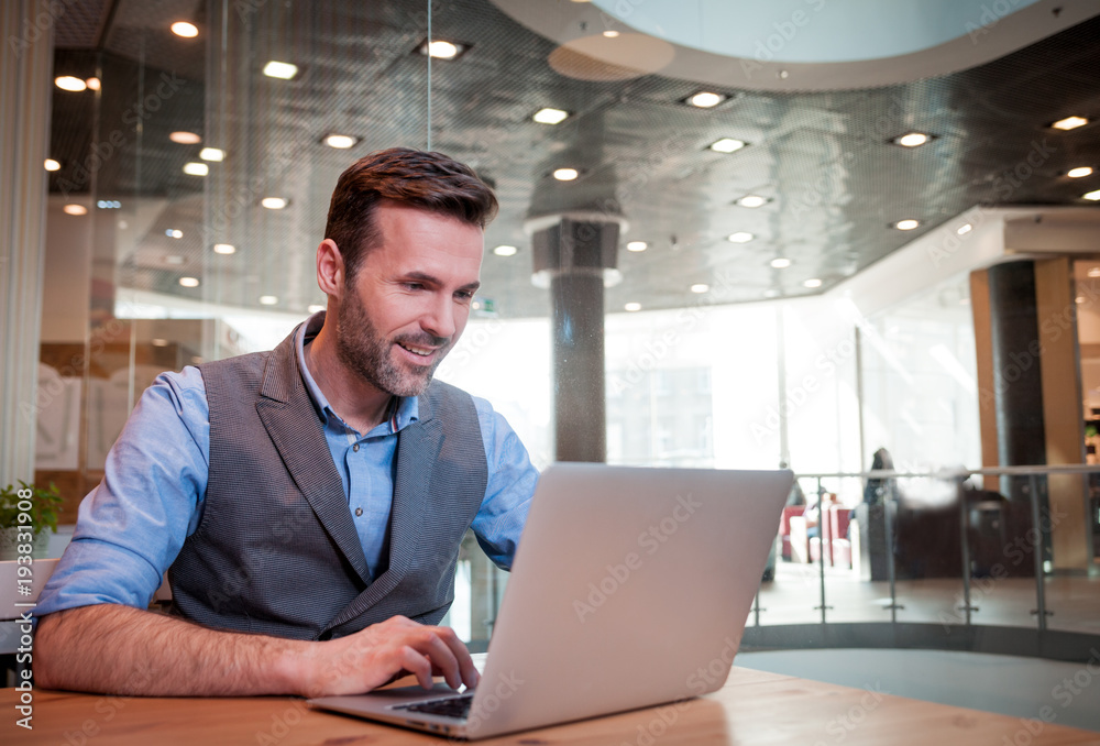 Confident businessman using laptop in modern interior