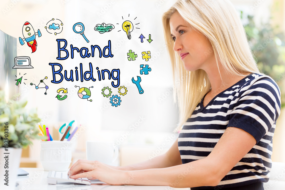 Brand Building with happy young woman sitting at her desk in front of the computer