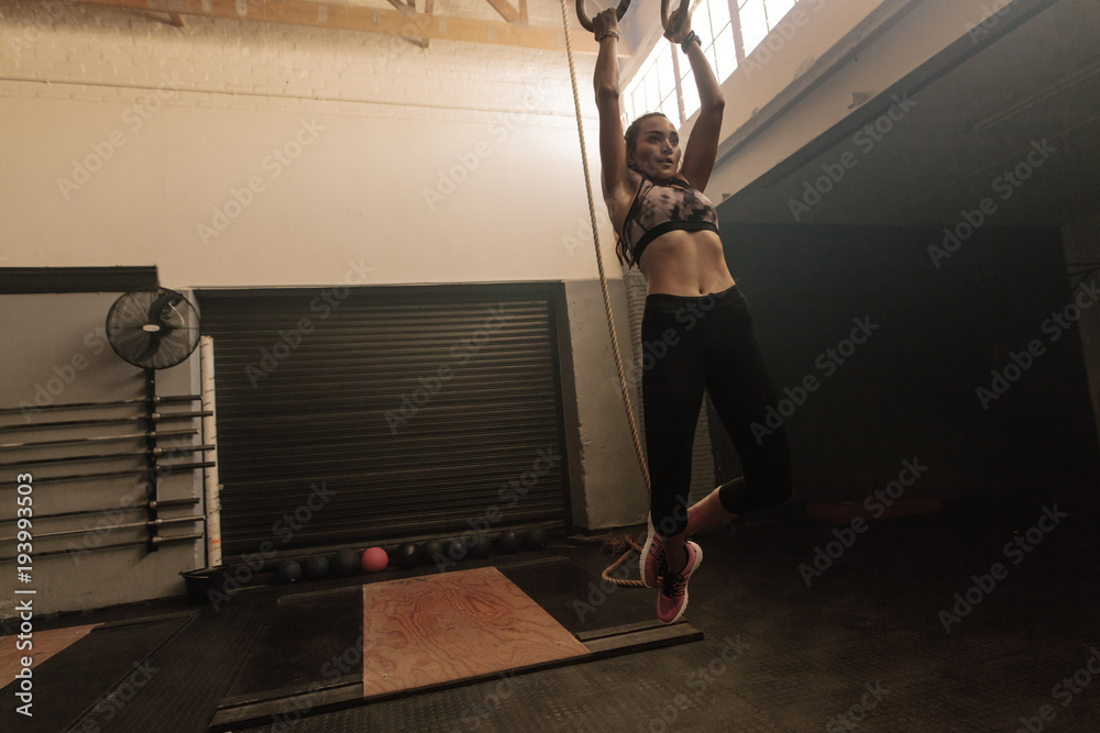 Woman exercising with dip rings at gym