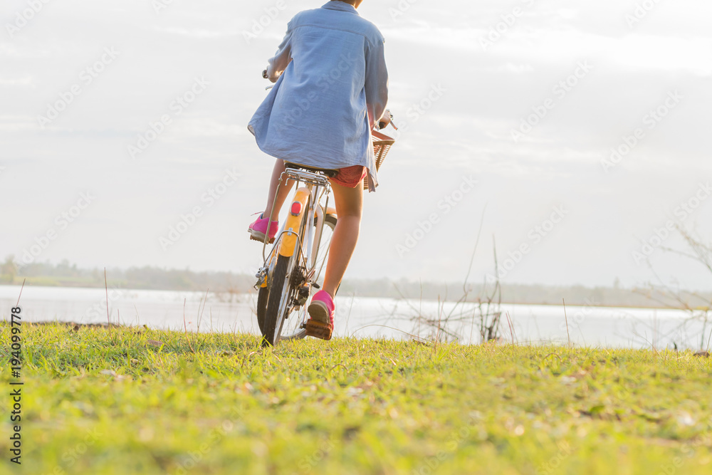 日落时分，年轻的亚洲女子在公园骑自行车