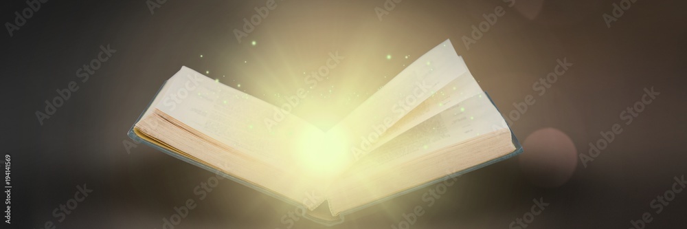 Opened book on gray background with light