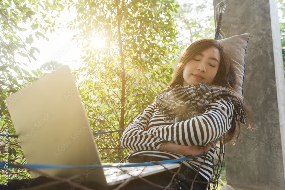 Young woman sleeping in hammock while use laptop, freelance life style conceptual, work anywhere