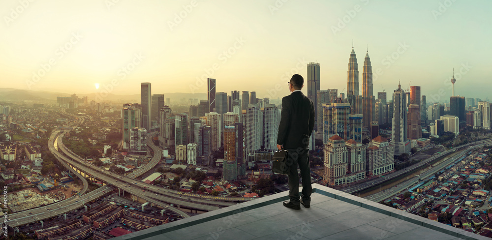 Businessman stand at rooftop looking great cityscape view and thinking business plan of the future .