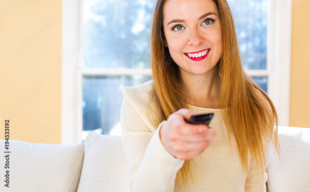 Young woman watching with remote control watching TV in the living room