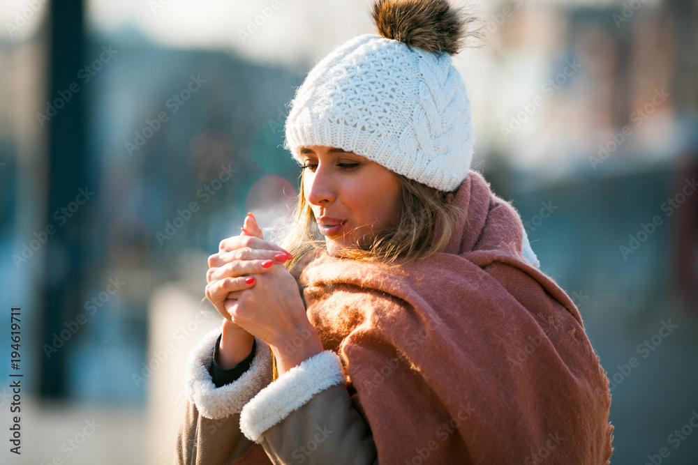 女人在寒冷的冬天用手呼吸以保暖