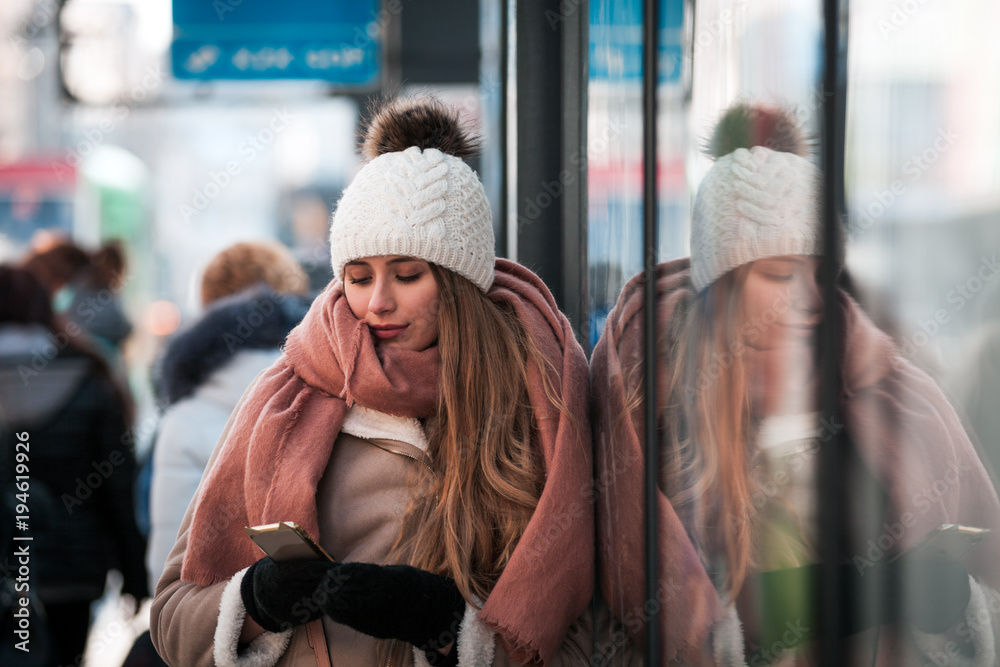 Woman using mobile phone standing out from the crowd at city street