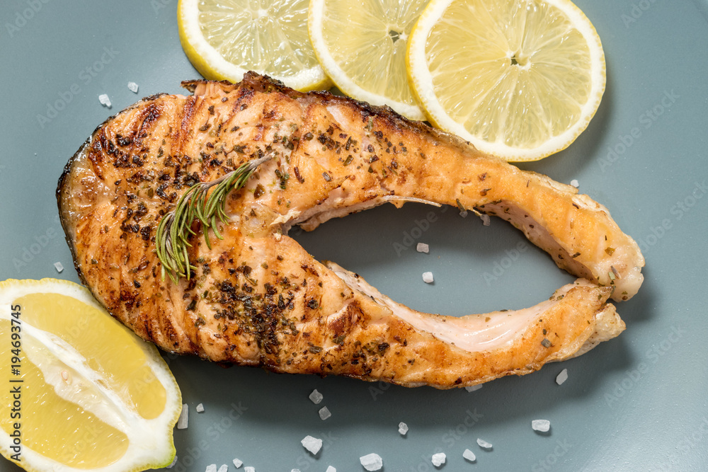 Salmon fillet. Grilled salmon with herb and lemon on plate. Fish roasted on a wooden background.