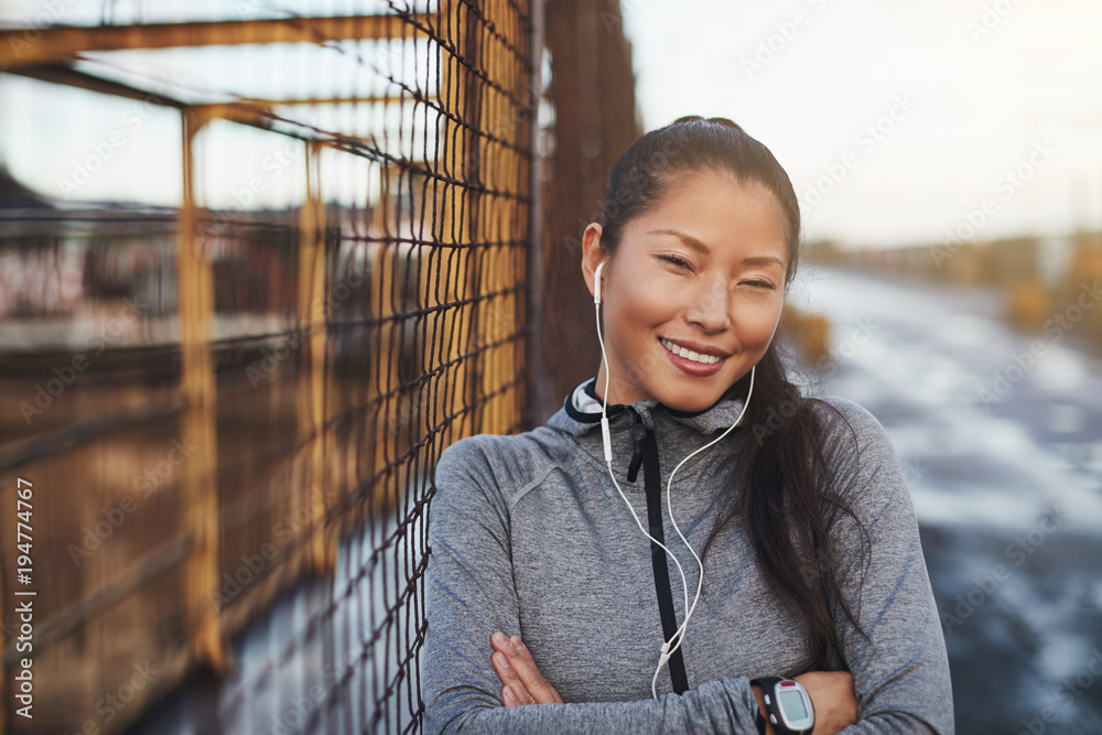 穿着运动服的年轻亚洲女性慢跑前听音乐