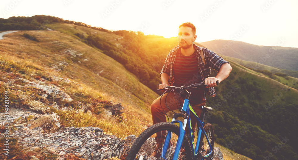 cycling. young man with bicycle on nature in mountains