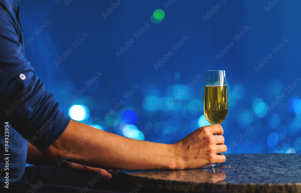 Man with a glass of white wine on a table high above the city at night