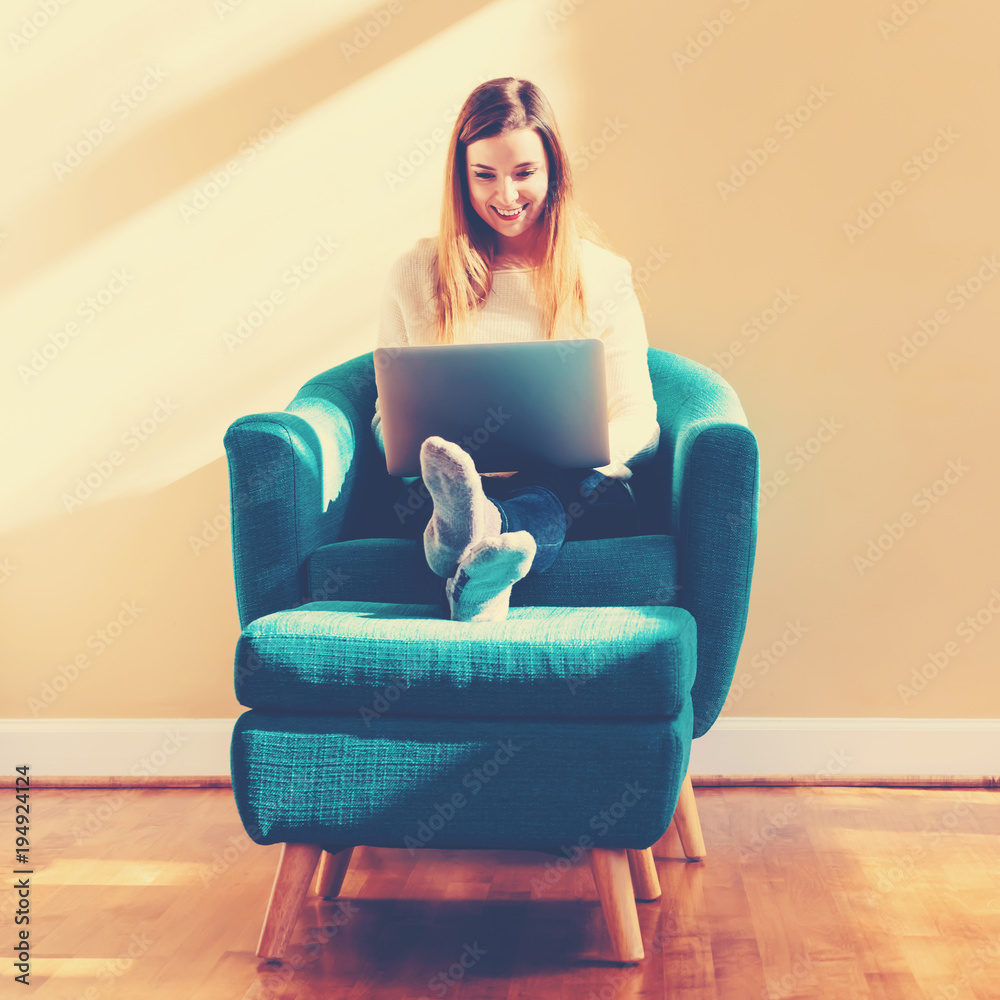 Happy young woman using her laptop computer at home