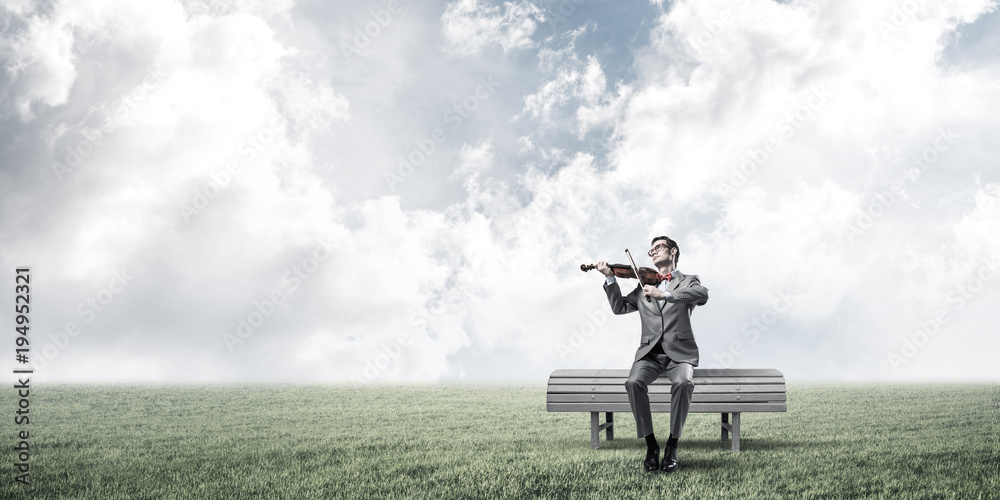 Handsome businessman in park on wooden bench play his melody