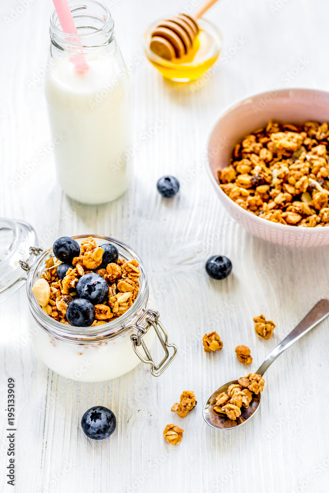 Homemade granola with blueberries in jar on white kitchen backgr