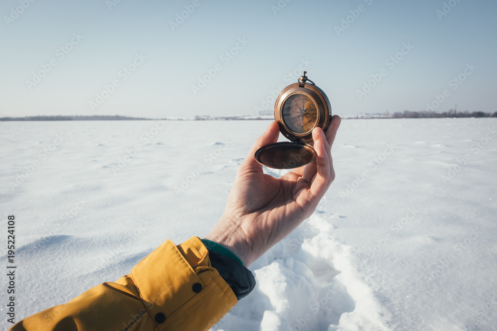 冬天雪地上手持指南针的人。旅行理念