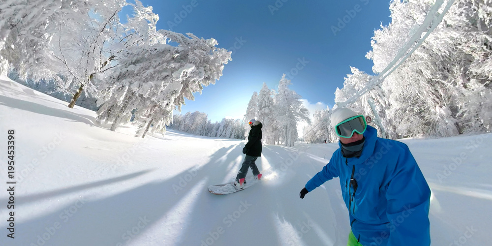 SELFIE：自由滑单板滑雪情侣在阳光明媚的山区骑行新鲜的粉雪