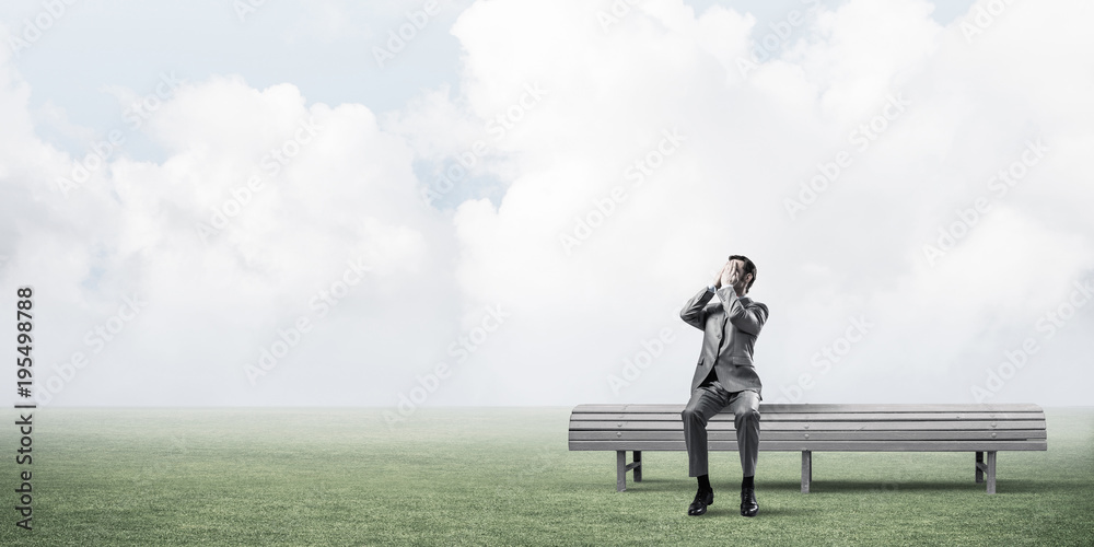 Young man in summer park on bench do not want to see anything