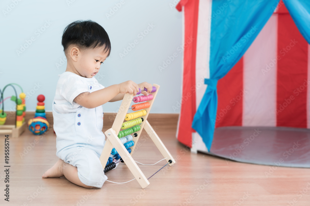 亚洲男婴学会数数。可爱的孩子在玩算盘玩具。小男孩在室内玩得很开心。