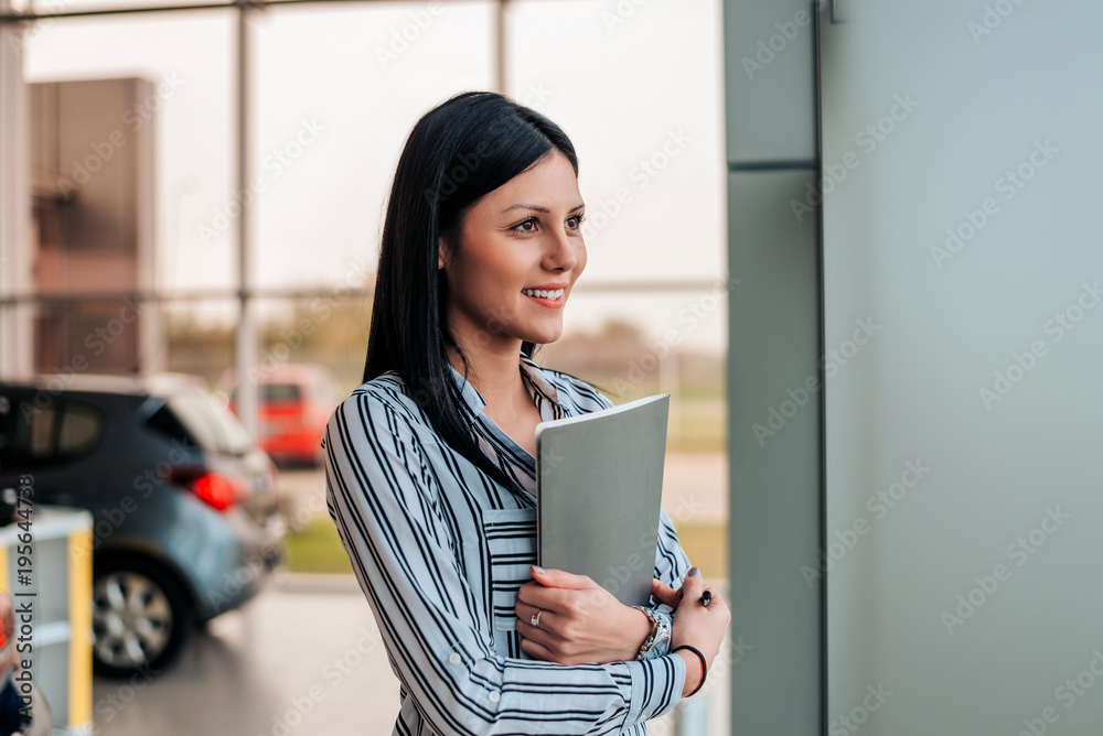 Side view of car saleswoman holding documents.