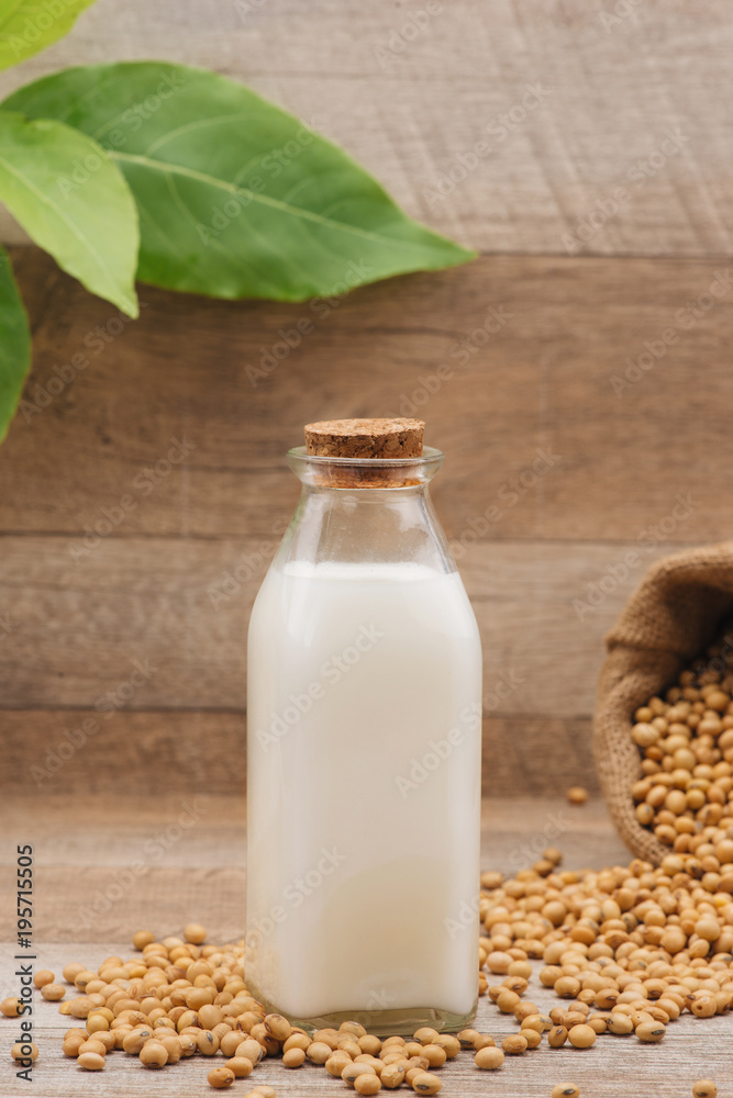 Bottle of soy milk and soybean on wooden table