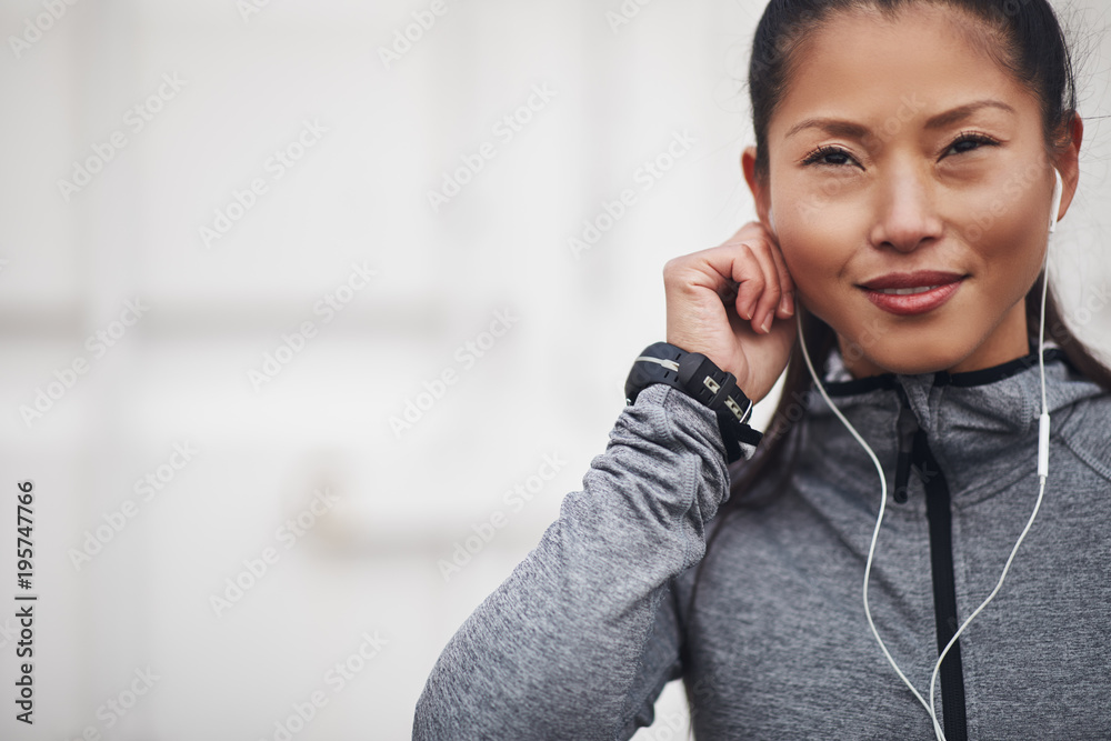 微笑的亚洲女人在慢跑前用耳机听音乐