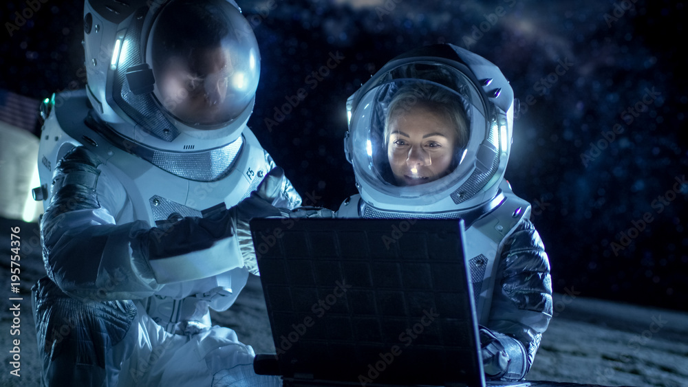 Two Astronauts Wearing Space Suits Work on a Laptop, Exploring Newly Discovered Planet, Communicatin