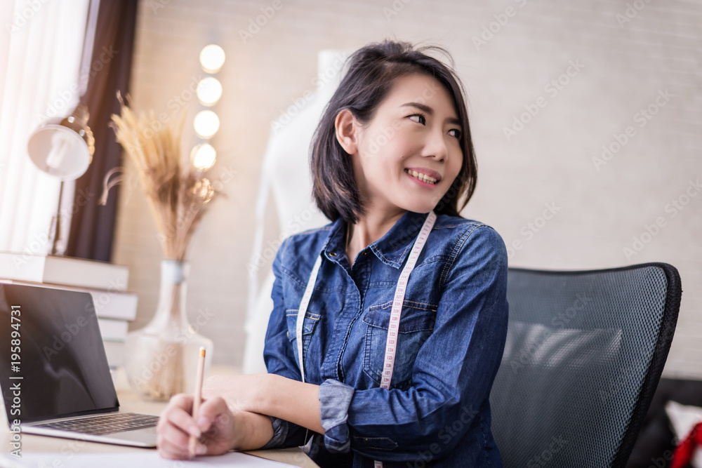 asian beautiful fashion designer  working at home with sketch book model stand